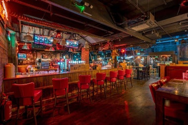 Interior of a pub with red chairs at the bar and tables set for service