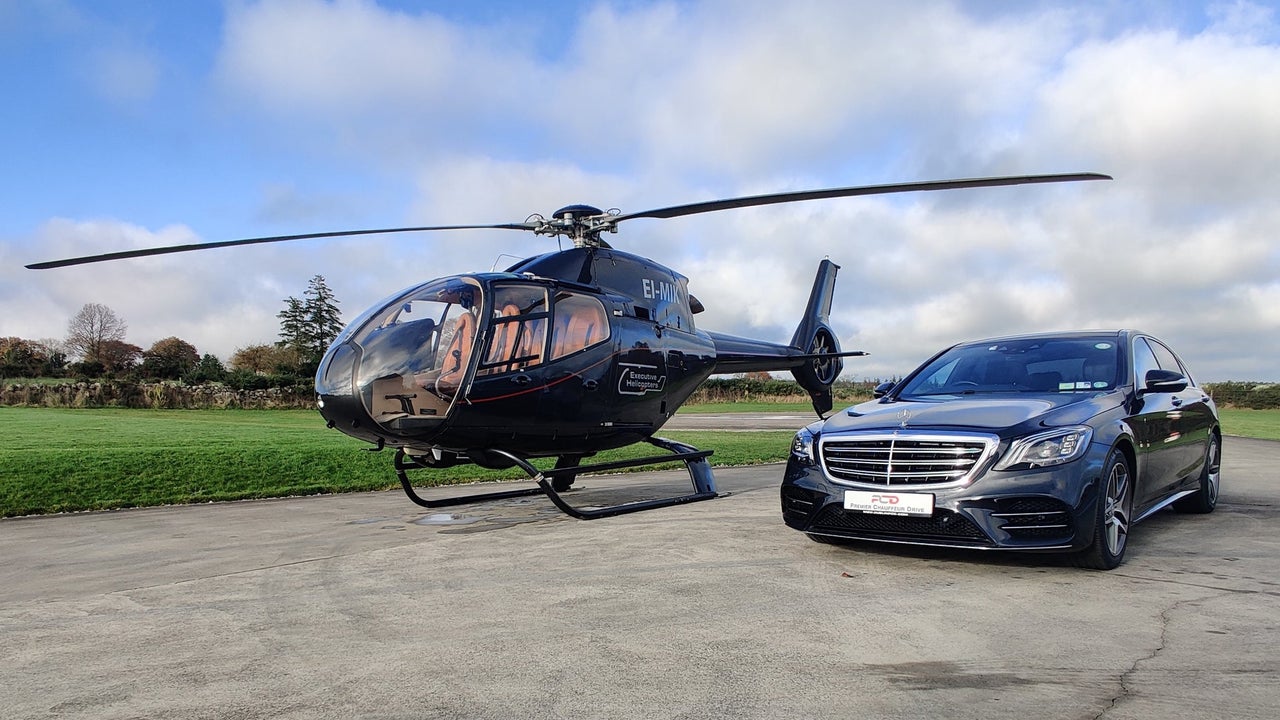 A luxury car parked beside a helicopter