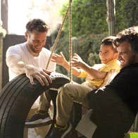 Two men and a boy are playing with a tyre swing.