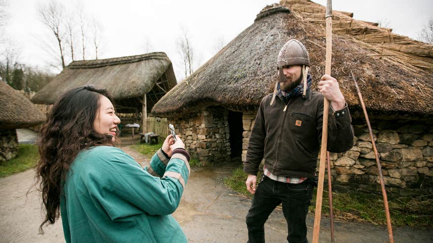 A woman taking a picture of a man posing in a Viking helmet at the Irish National Heritage Centre in County Wexford.