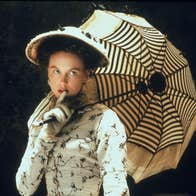 A well-dressed woman with a hat and parasol.