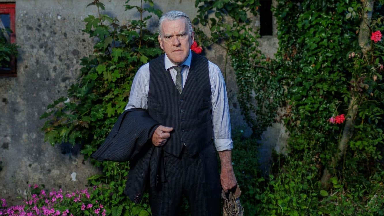 The Man In The Woman’s Shoes at Backstage - a grumpy looking man in shirt and tie holding a jacket in one hand and an old shoe in the other.