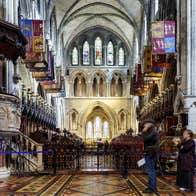 Nave of a church with banners on either side and stain glass windows in the background