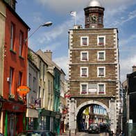 Youghal Clock Gate Tower, shop fronts and cars on a busy street