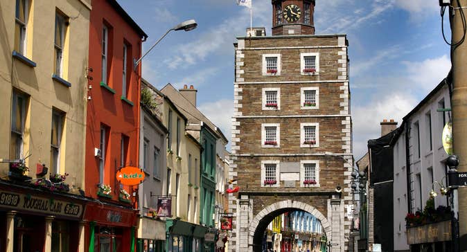 Youghal Clock Gate Tower, shop fronts and cars on a busy street
