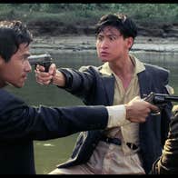A man pointing a pistol at a man who is pointing a pistol at a third man.