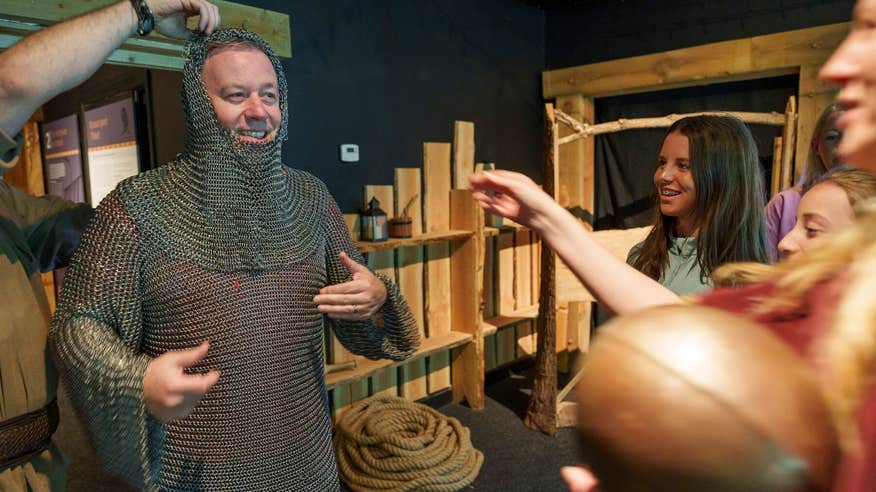 Man wearing chain mail with family at the Knights and Conquests Heritage Centre.