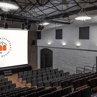 A theatre with tiered seating facing a cinema screen
