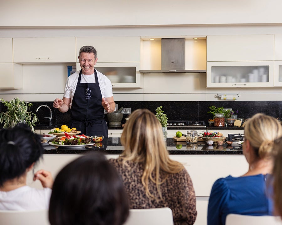 A chef smiling at his class during a cookery demonstration