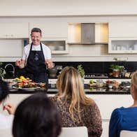 A chef smiling at his class during a cookery demonstration