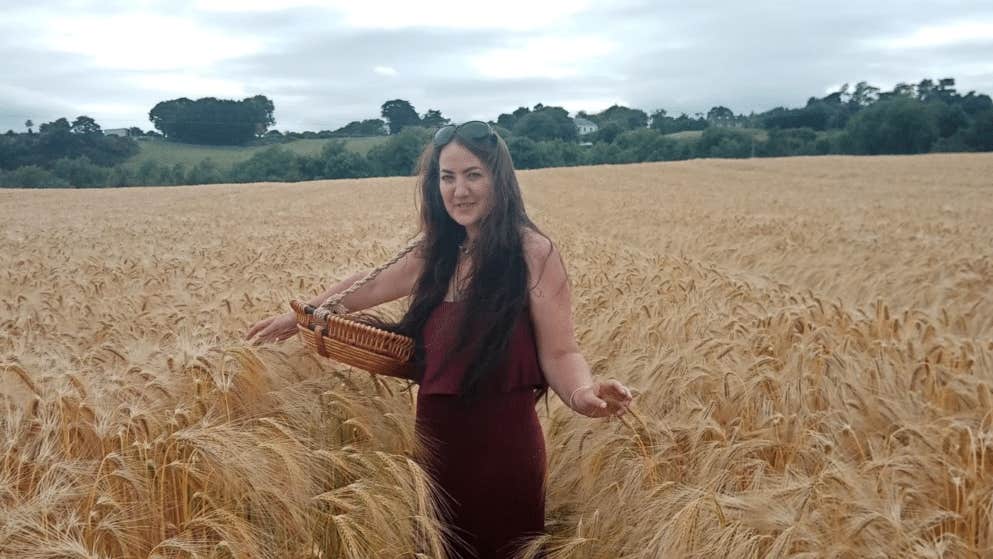 A woman standing in the middle of a field of ripe corn.