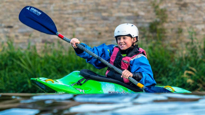 A young person kayaking on the river along the Suir Blueway