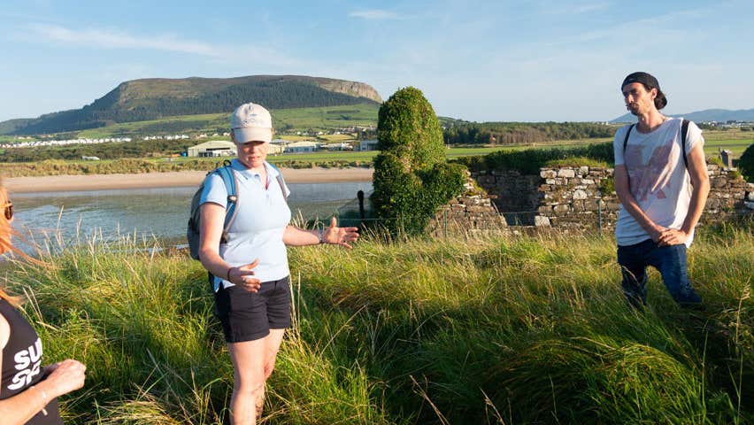A couple standing either side of a guide on a coastal walking tour