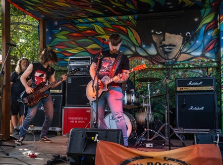 A band playing their guitars on the stage in The Bloody Stream