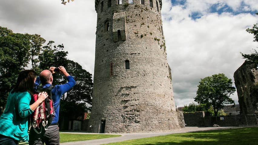 Two people pointing their camera up at a tower