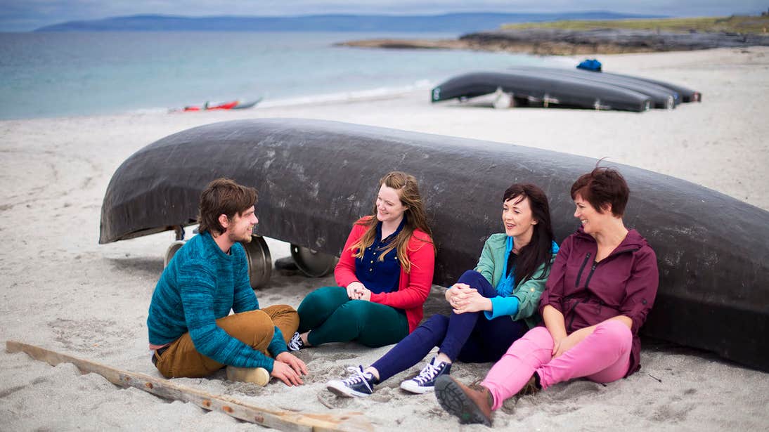 Four people sitting beside a boat on Inisheer Island, Aran islands, Galway