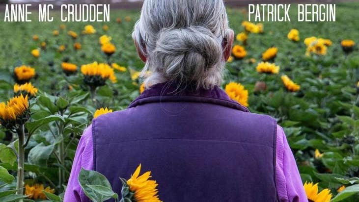 Film poster showing rear view of women in purple jacket standing in a field of sunflowers