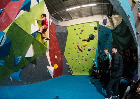 A man on a climbing wall with two people watching