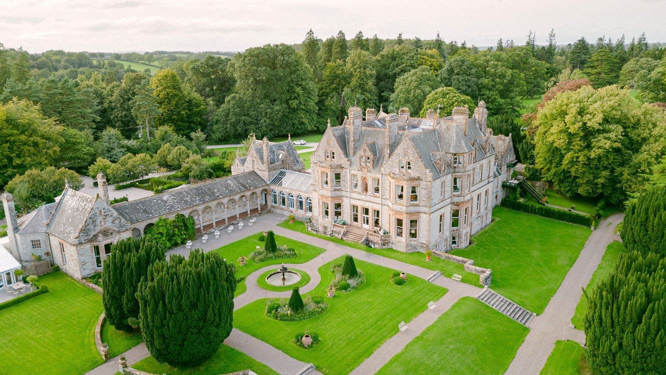Aerial view of a large country estate house with a formal lawn area
