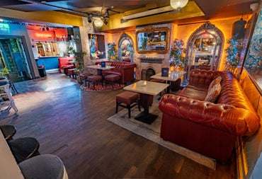 Orange coloured bar interior with leather couches tables and high stools