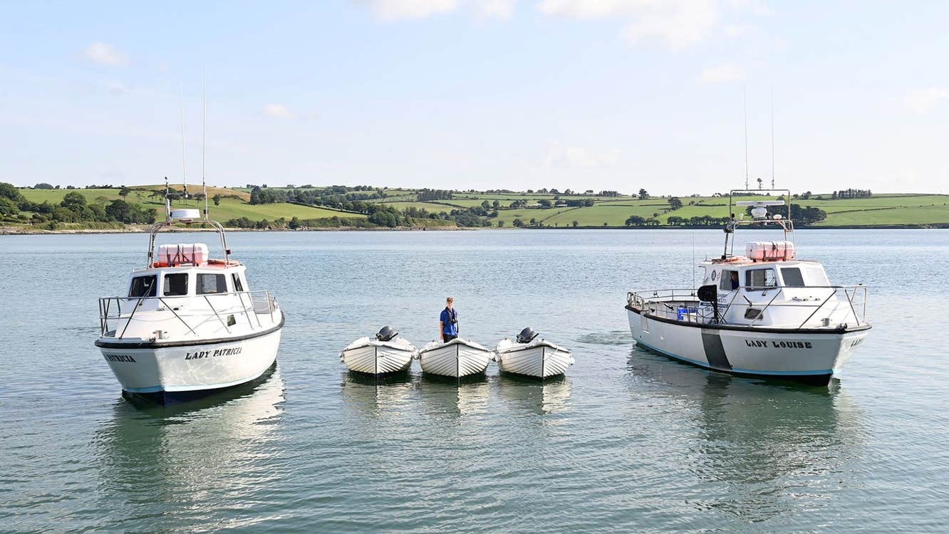 Two small fishing vessels with three smaller self drive boats moored between them