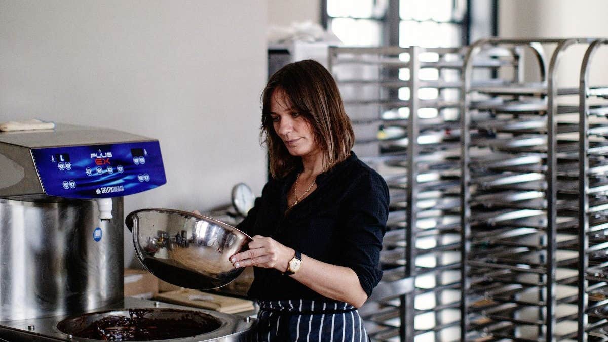 A person wearing an apron holding a mixing bowl