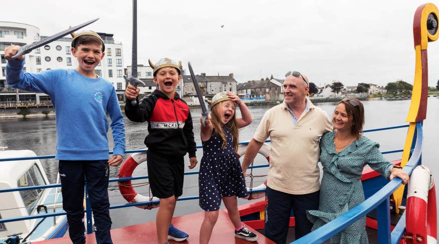 Family with three young kids holding swords on Viking Boat Tour in Athlone.