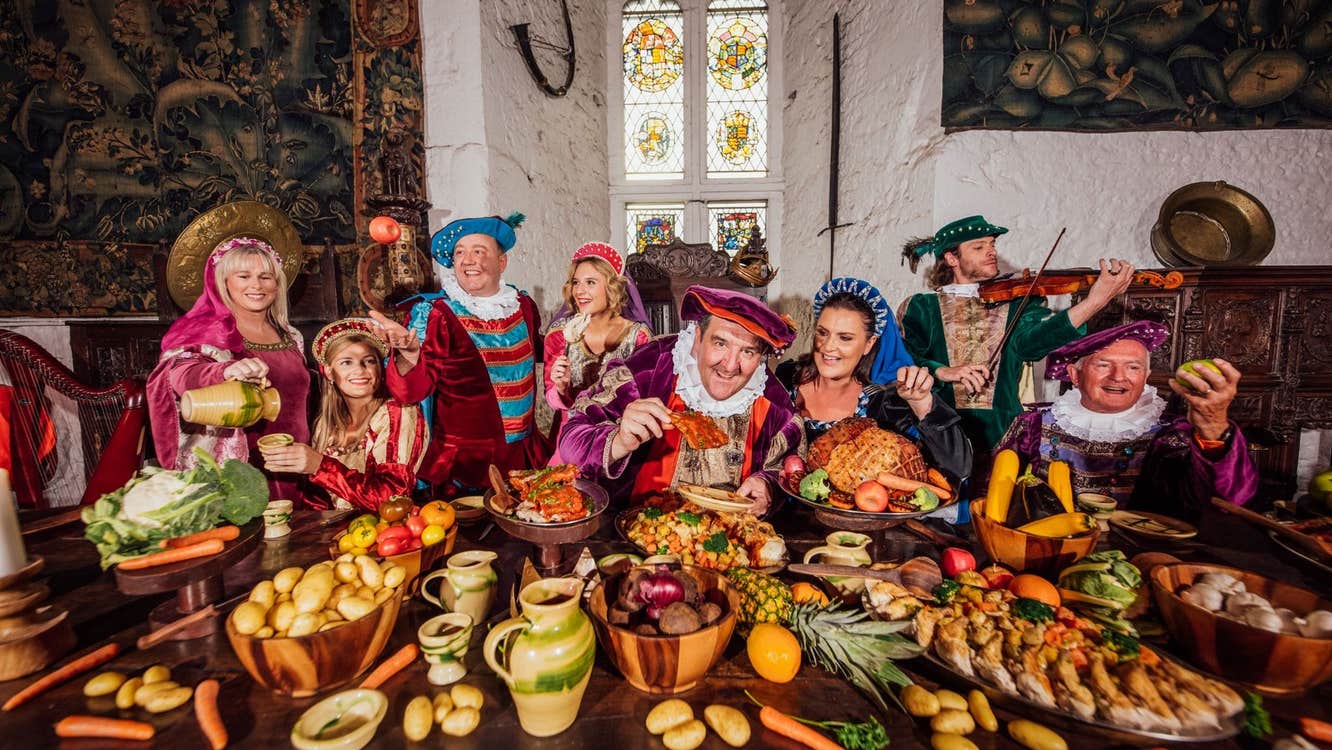 People in medieval costume posing at a table laid out with food and drink