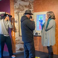 Visitors being photographed using headphones and interactive displays inside a museum