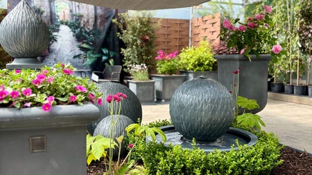 A selection of planters with pink flowers and a water fountain