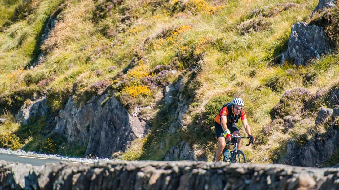 A person cycling past a stone wall on the Ring of Kerry, County Kerry