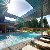 Outdoor pool surrounded by wooden decking and loungers with cushions