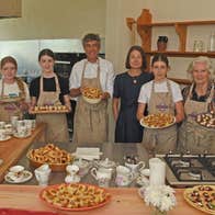People holding full platters while standing in front of a counter with other baked goods on display