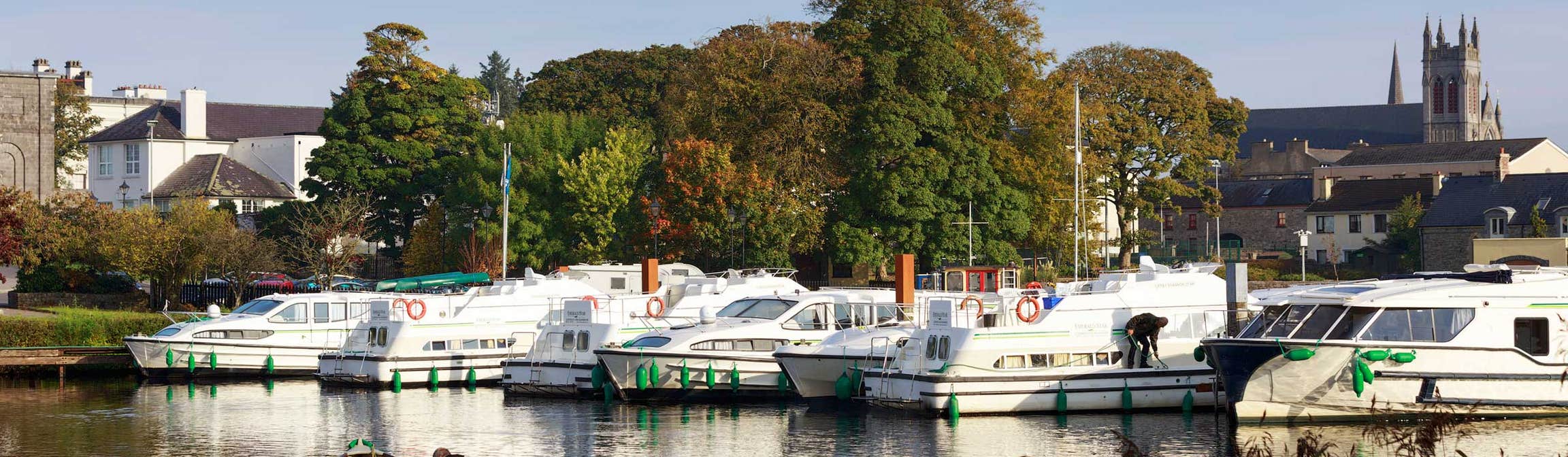 Boats in a marina with a backdrop of trees and a church in Carrick-on-Shannon, County Leitrim