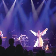 4 people on a stage playing musical instruments and singing.