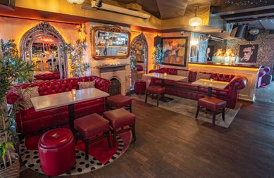 The lounge with red leather sofas and large ornate mirrors hanging on the walls