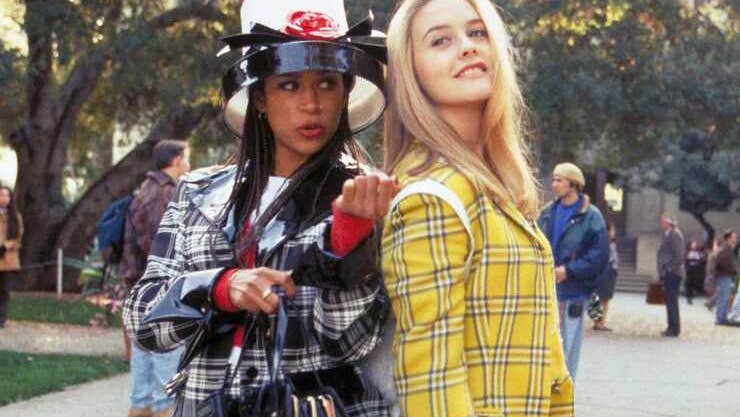 2 young women in different coloured checked outfits standing back to back outdoors
