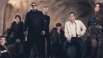 A group of people standing and sitting under a cellar brick arch.