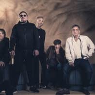 A group of people standing and sitting under a cellar brick arch.