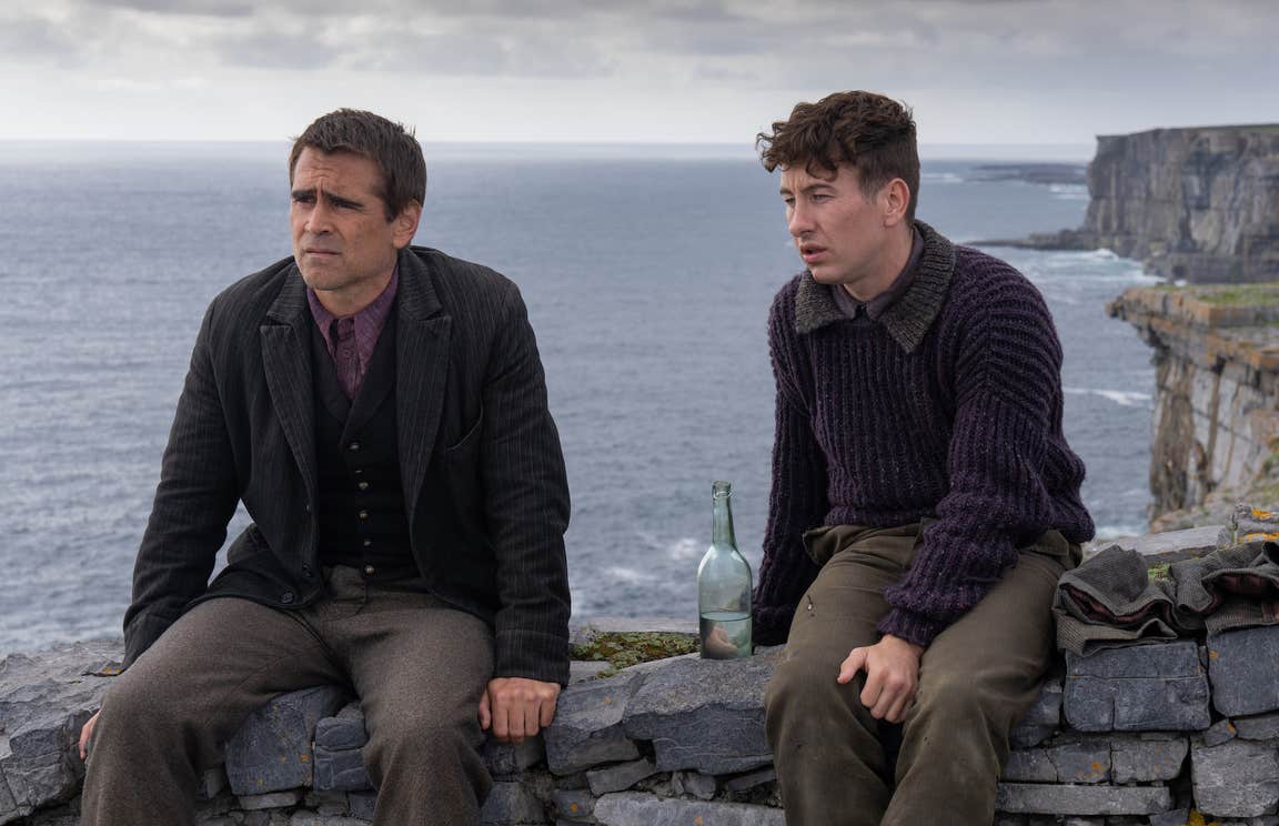 Colin Farrell and Barry Keoghan sit on top of a stone wall on Inis Mor with the Atlantic ocean as the backdrop.