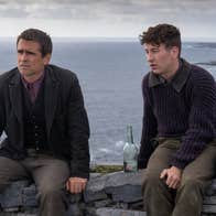Colin Farrell and Barry Keoghan sit on top of a stone wall on Inis Mor with the Atlantic ocean as the backdrop.