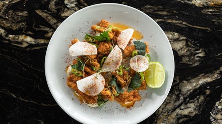 A dish from the menu at Charlotte Quay Restaurant served on a white plate with a slice of lime on the side