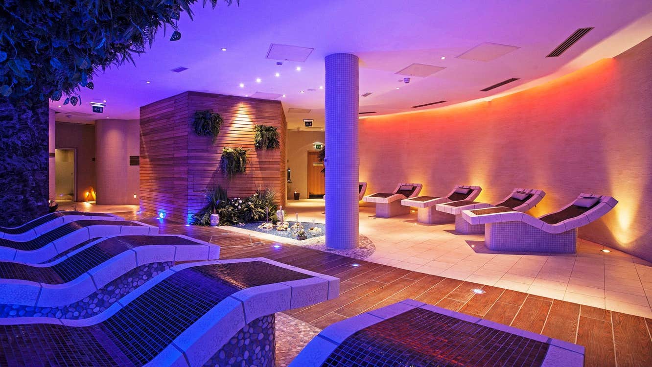 A dimly lit spa with purple lighting and reclined seating