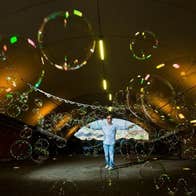 Distant view of man with arms outstretched in pale blue with area covered in bubbles of different sizes.