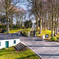 Entrance to a shrine with trees and a miniature traditional cottage