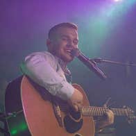 Singer, songwriter Dan McCabe playing a guitar and singing into mic on a stand.