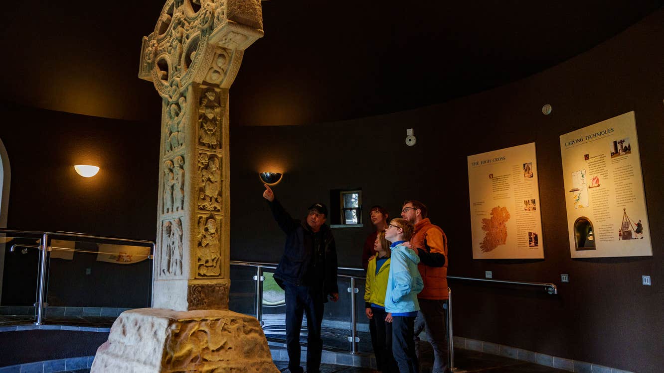 Family with a guide at a stone high cross at Clonmacnoise