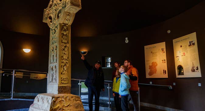 Family with a guide at a stone high cross at Clonmacnoise