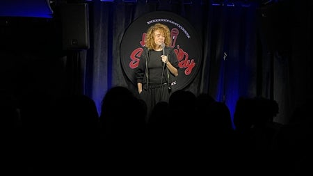 A comedian holding a microphone on a stage