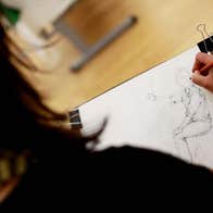 Photo © DK Photo. National Gallery of Ireland. Looking over the shoulder of a someone sketching a figure on a white piece of paper.